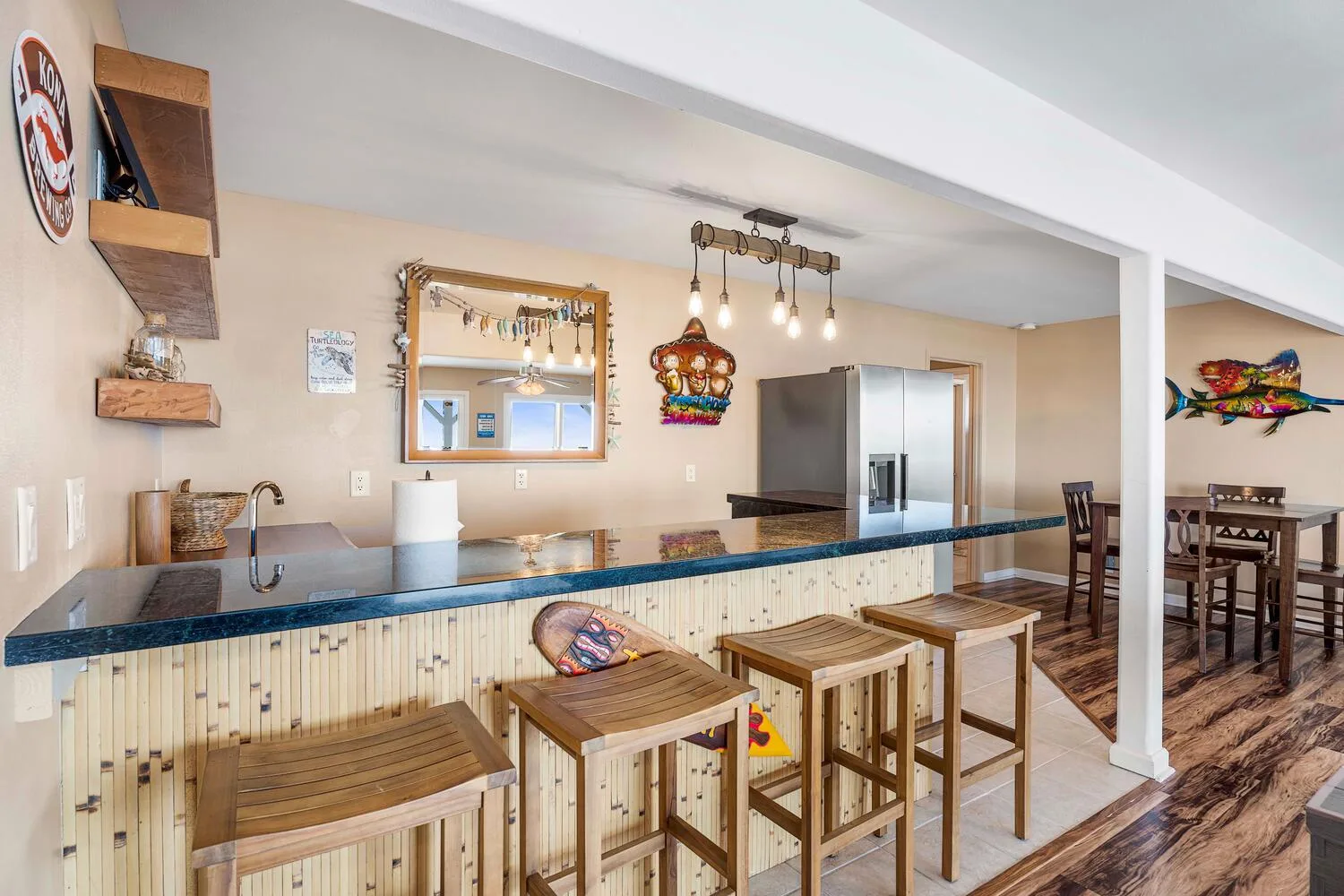 Cocina y comedor con una barra larga, taburetes y una mesa.