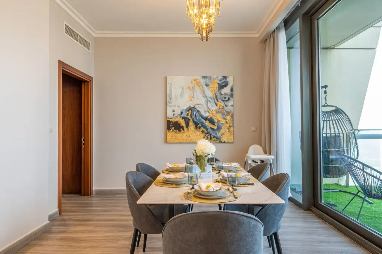 A dining area with a set table beside large glass doors opening onto a patio.