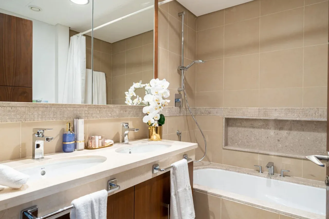 A bathroom with a double sink vanity, bathtub, and shower.