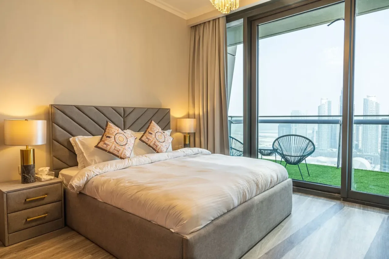 A bedroom with a neatly made bed and large windows overlooking the water.