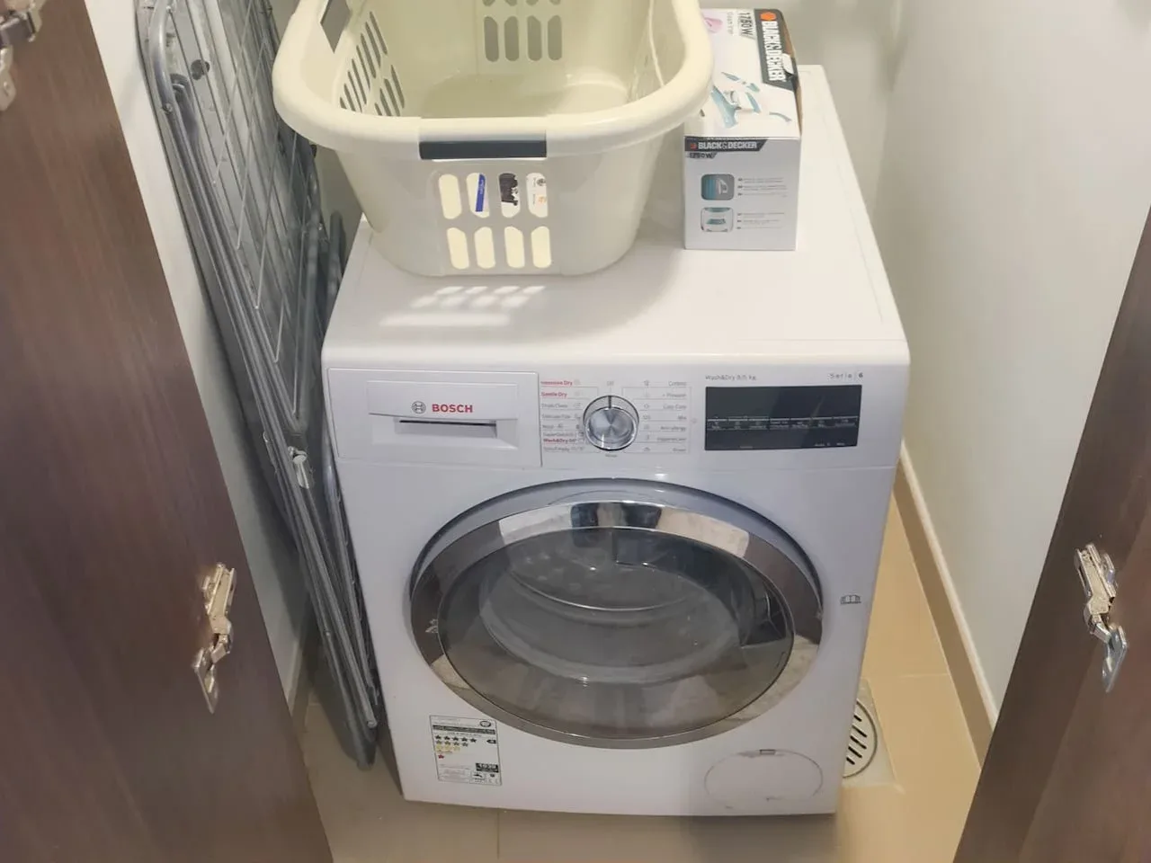 A front-loading washing machine sits in a compact laundry area.