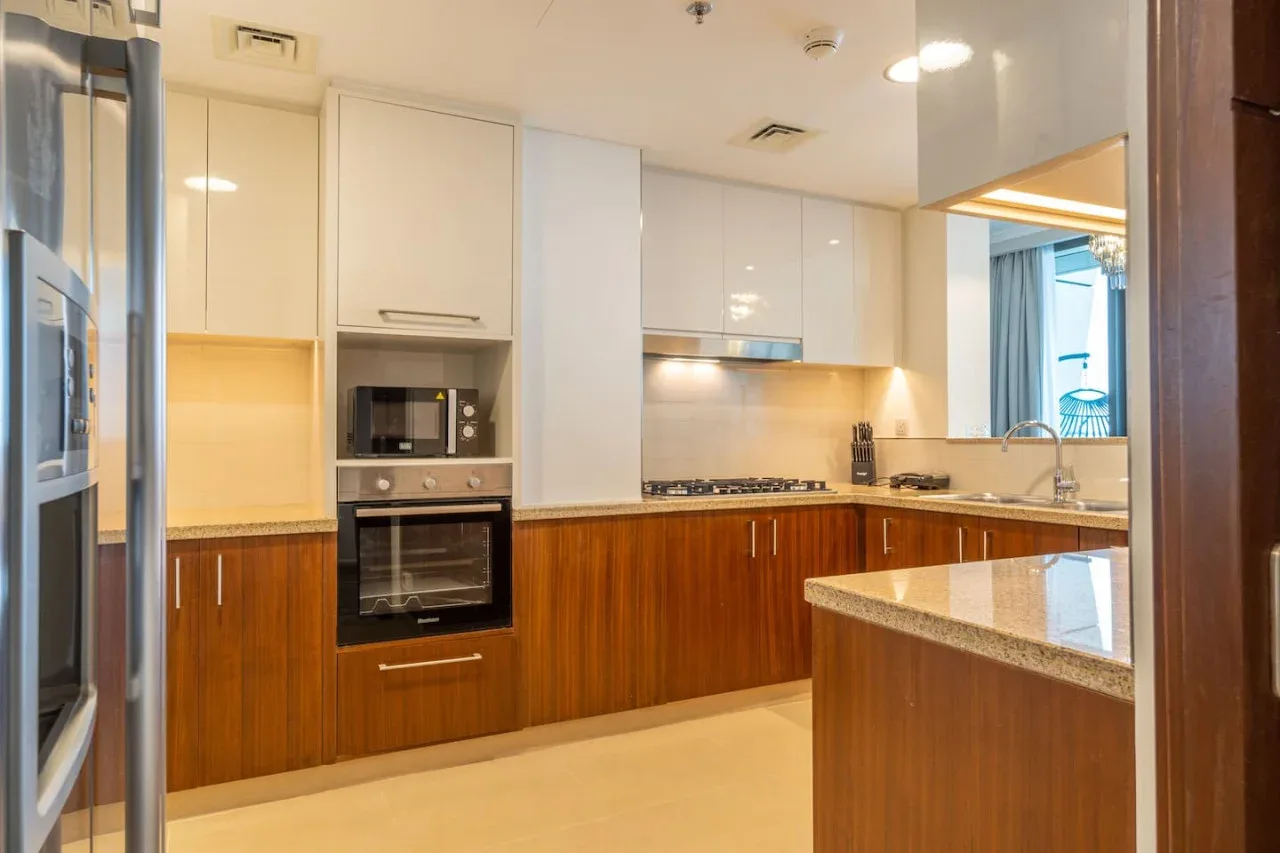 A modern kitchen with wood cabinetry, built-in appliances, and light countertops.