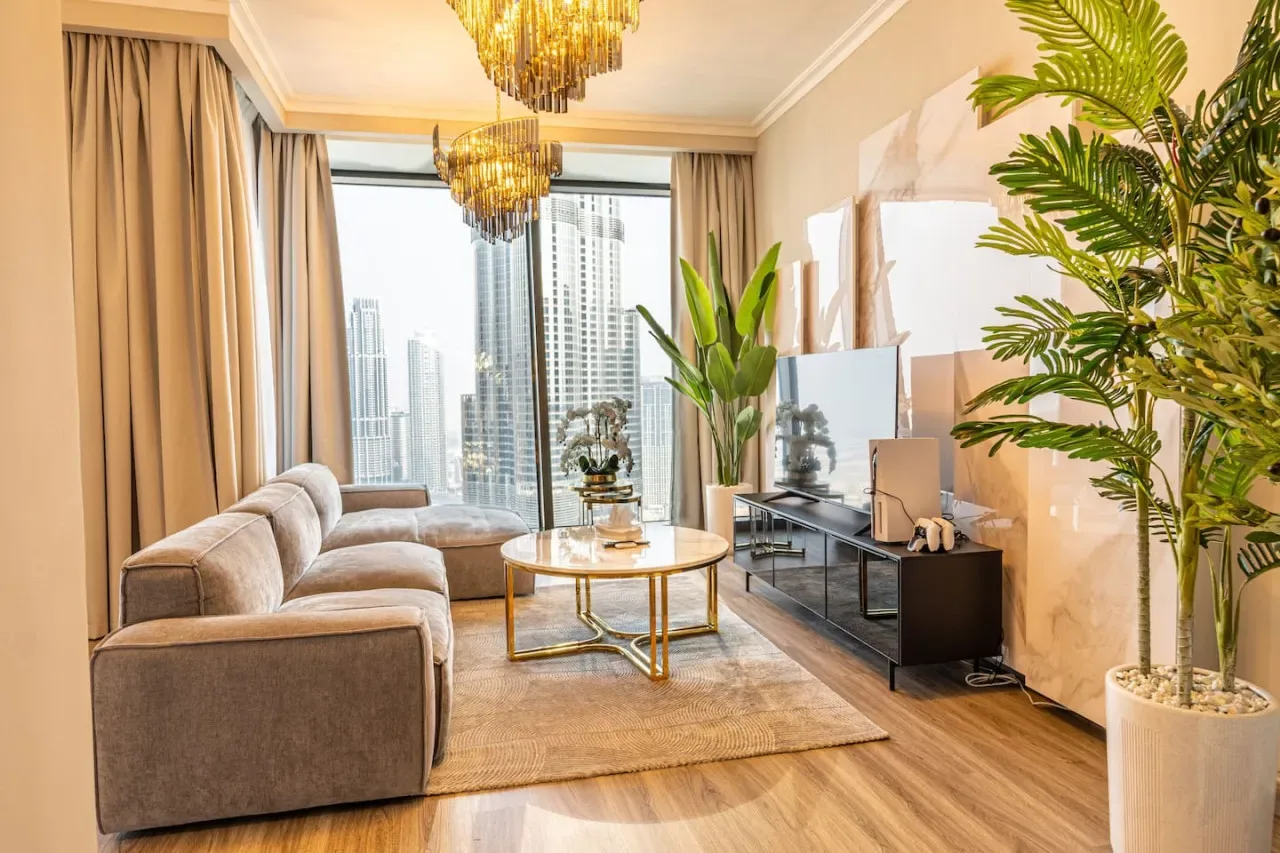 A bright living room with seating, a glass coffee table, and large windows.