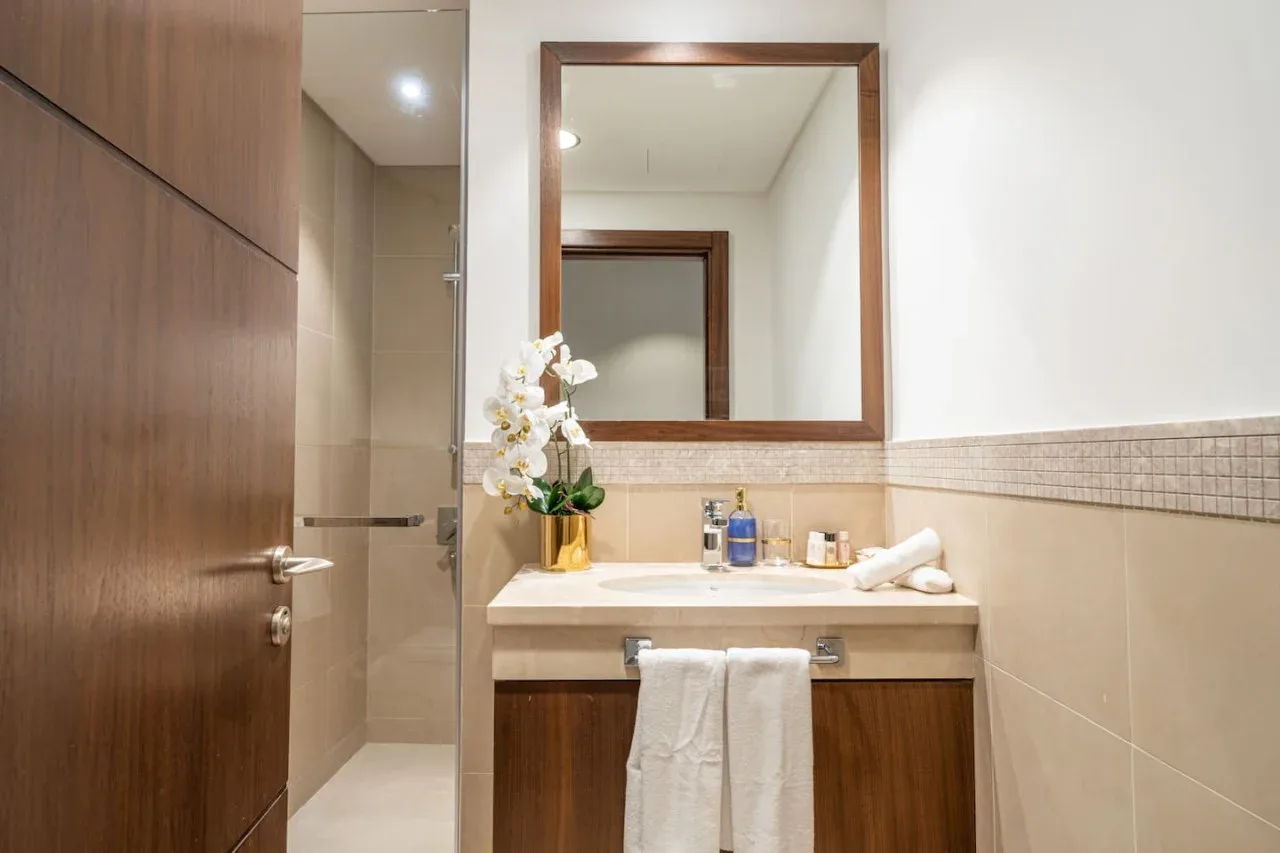 A bathroom vanity with a mirror, flowers, and folded towels.