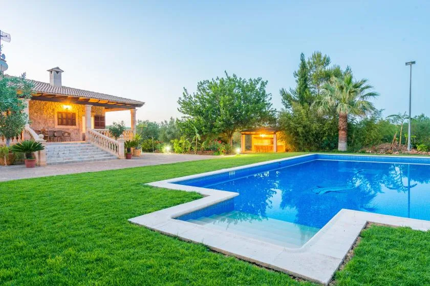 An outdoor swimming pool beside a lawn and a covered patio.