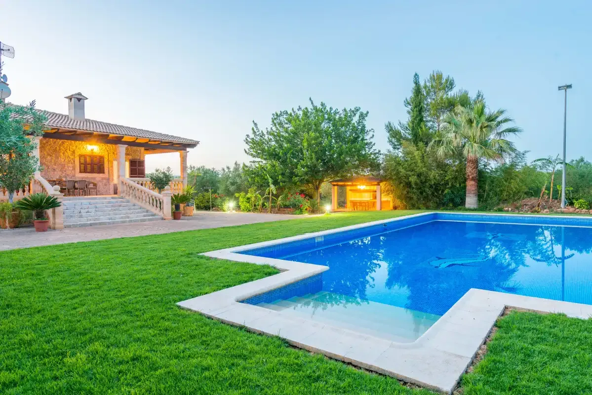 An outdoor swimming pool beside a lawn and a covered patio.