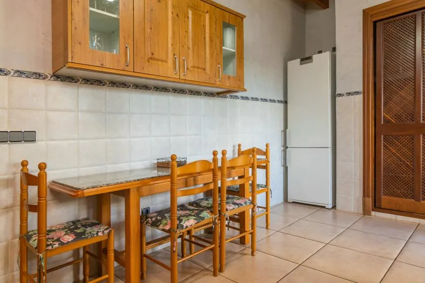 A tiled dining area with a wooden table and matching chairs beneath wall cabinets.