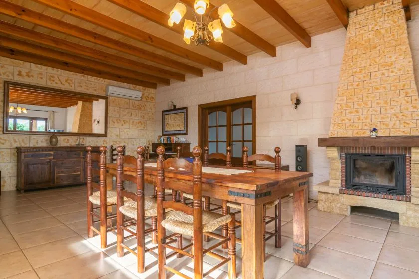 A dining room with a long wooden table beneath exposed ceiling beams.