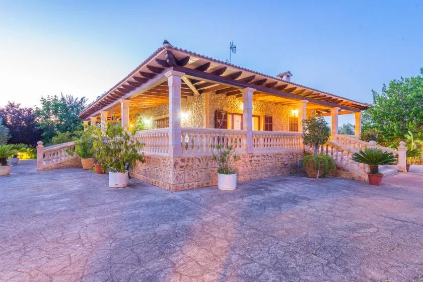 A house with a covered porch and paved courtyard at dusk.