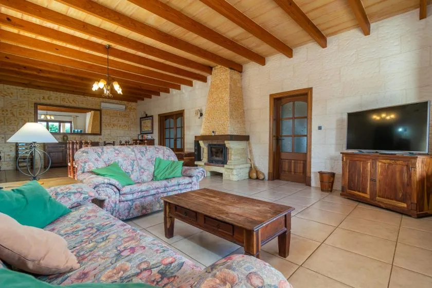 A living room with patterned seating, a wooden coffee table, and a television.
