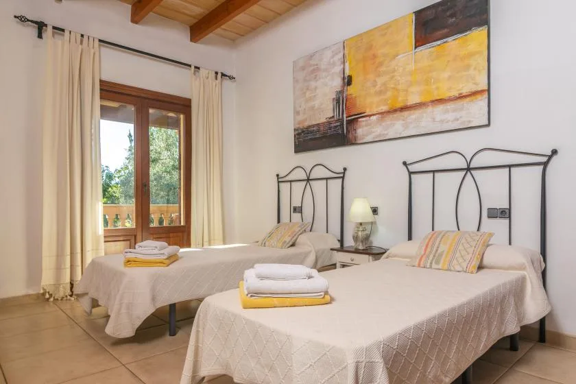 A bedroom with two beds, bedside lamps, and a large abstract painting.