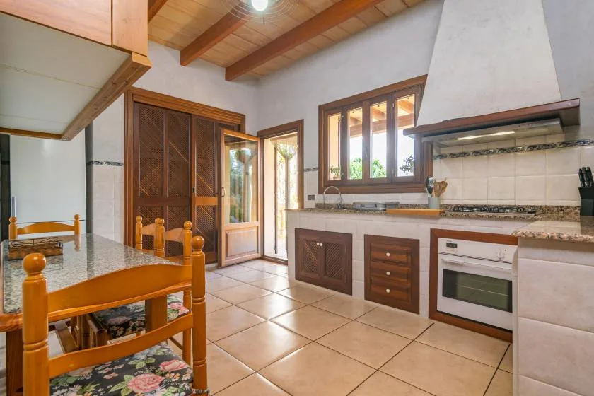 A kitchen with a dining table, wooden cabinets, and a tiled floor.