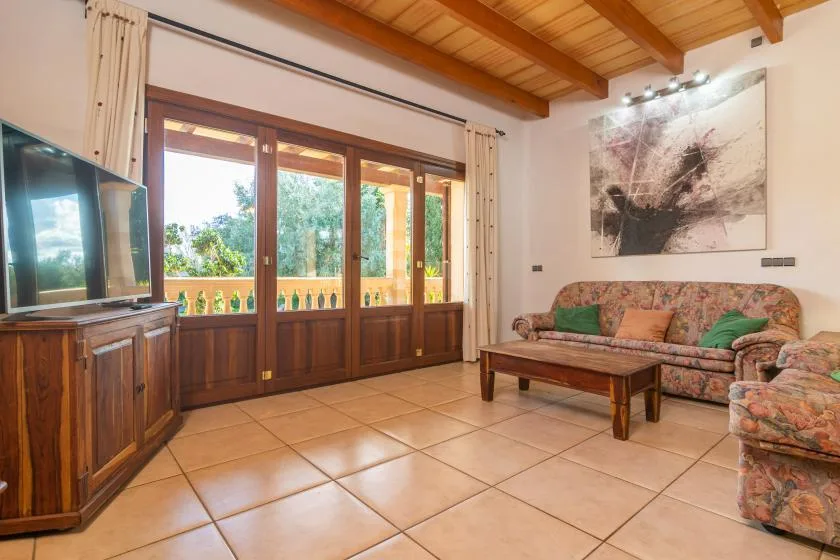 A living room with seating, a coffee table, and glass doors opening to a balcony.