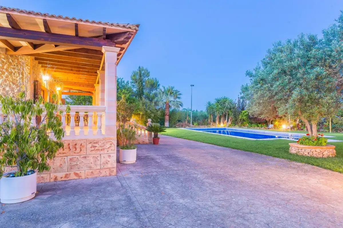 An outdoor pool beside a covered stone patio and paved terrace.