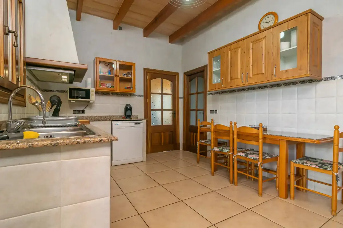 A kitchen with wooden cabinets, a counter, and a dining table.