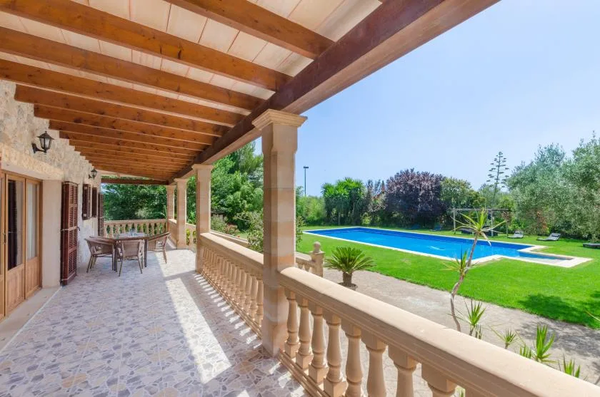 A covered patio overlooks a blue swimming pool and landscaped lawn.