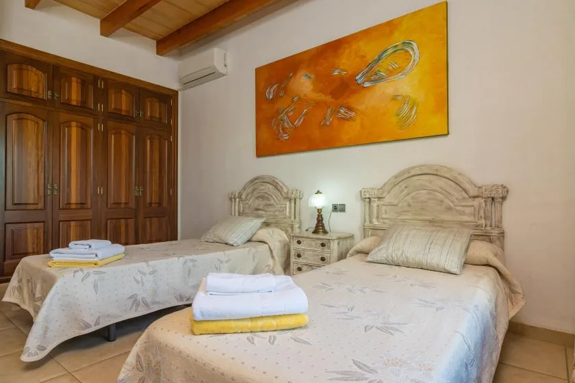 A bedroom with two beds, bedside tables, and a large abstract painting.
