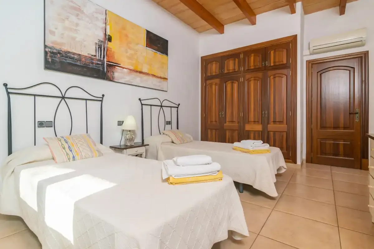 A bedroom with two beds, wooden wardrobes, and exposed ceiling beams.