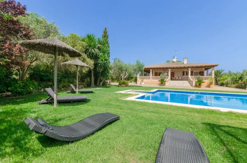 A landscaped garden with a swimming pool and a covered patio.