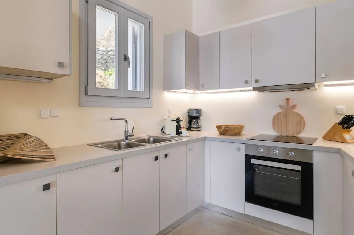 A bright kitchen with white cabinets and a countertop stove.