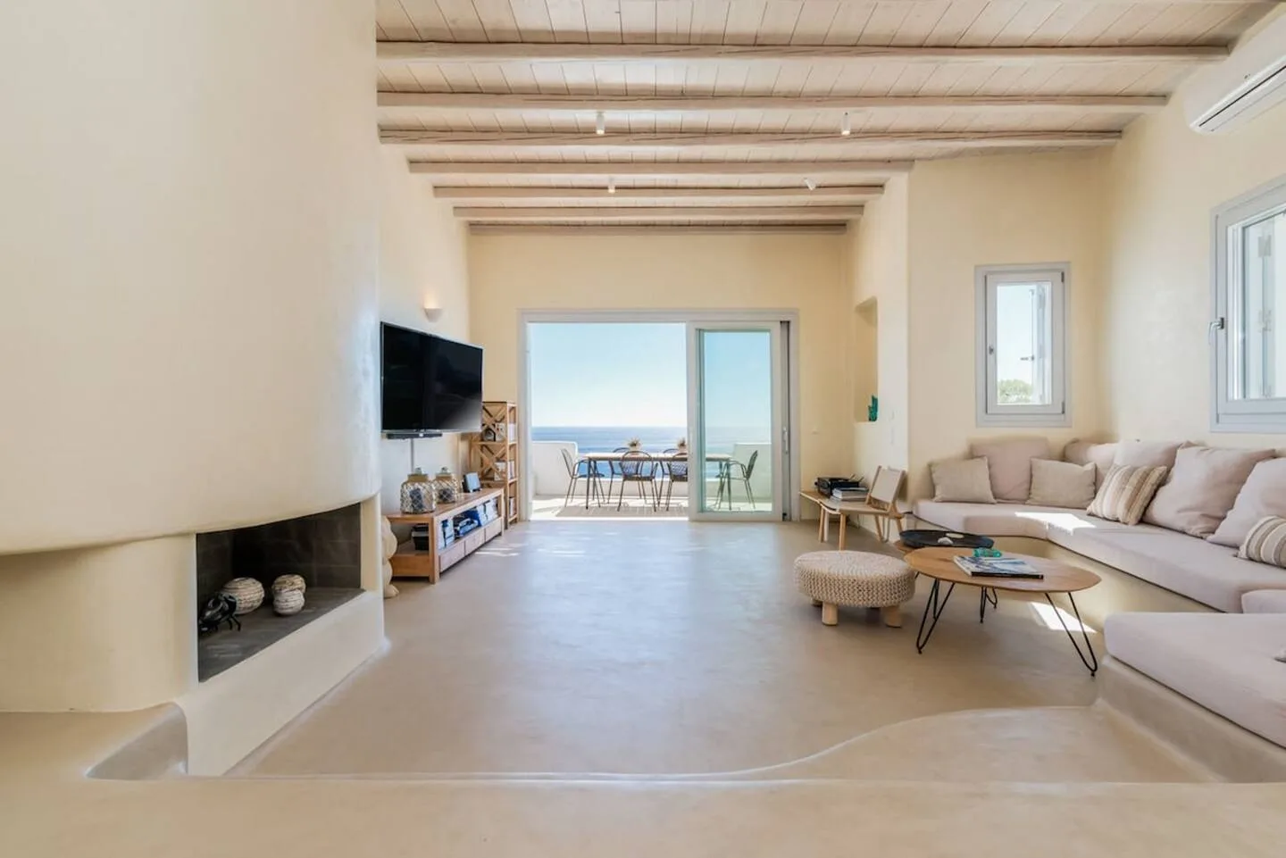 A bright living room opens onto a balcony with a view of the sea.