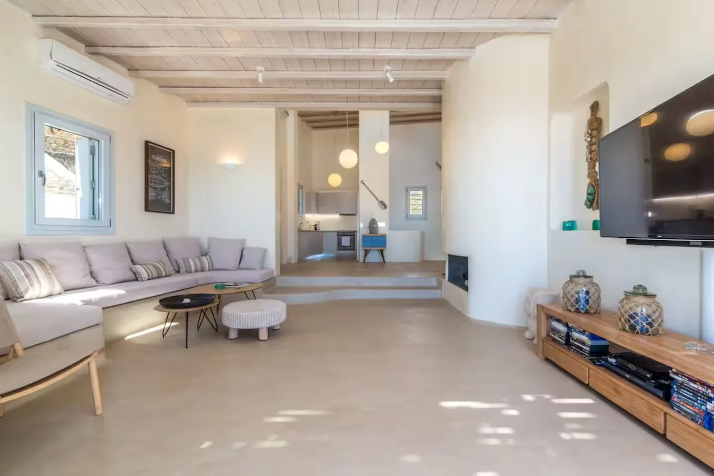 A bright living room with seating, a television, and a raised dining area.