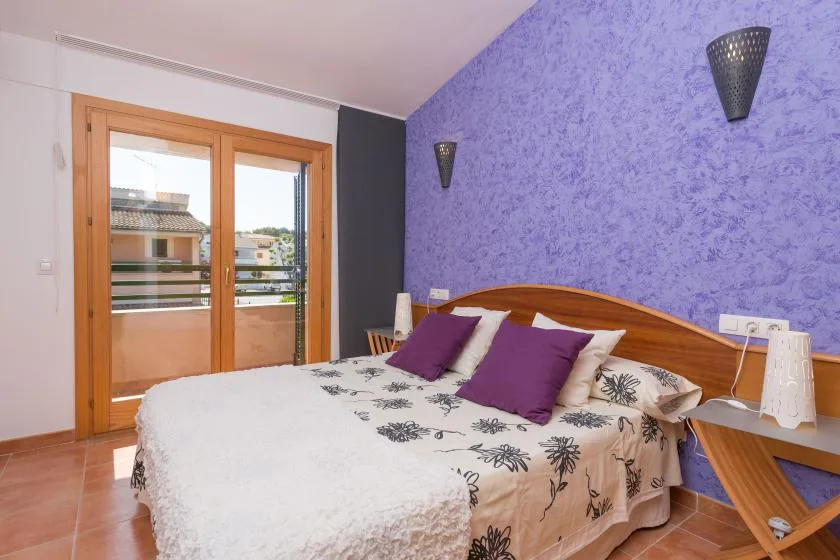Dormitorio con una cama doble y puertas corredizas de vidrio que dan a un balcón.