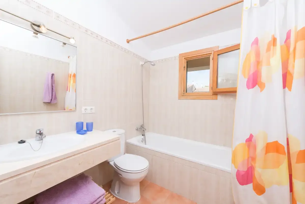 Un baño con bañera, lavabo y una cortina de ducha colorida.