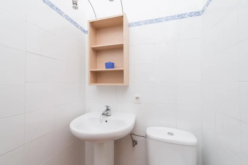 Un baño alicatado con lavabo de pedestal e inodoro.