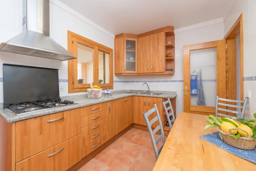 Una cocina luminosa con gabinetes de madera, una estufa y una mesa de comedor.