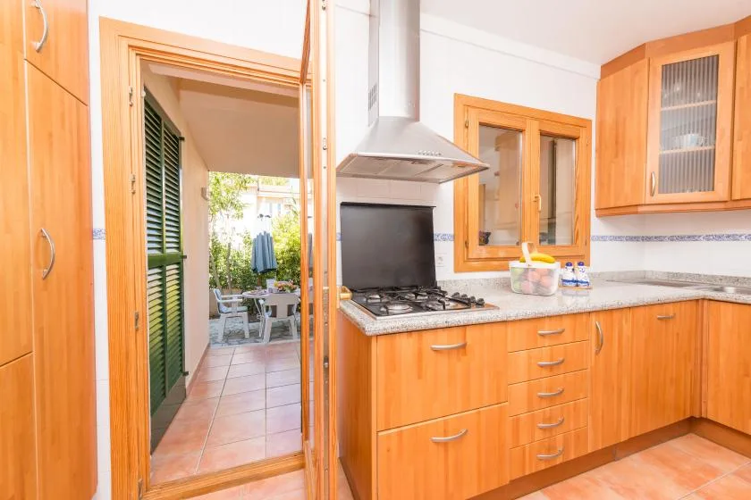 Una cocina luminosa con armarios de madera, una encimera y una puerta al patio.