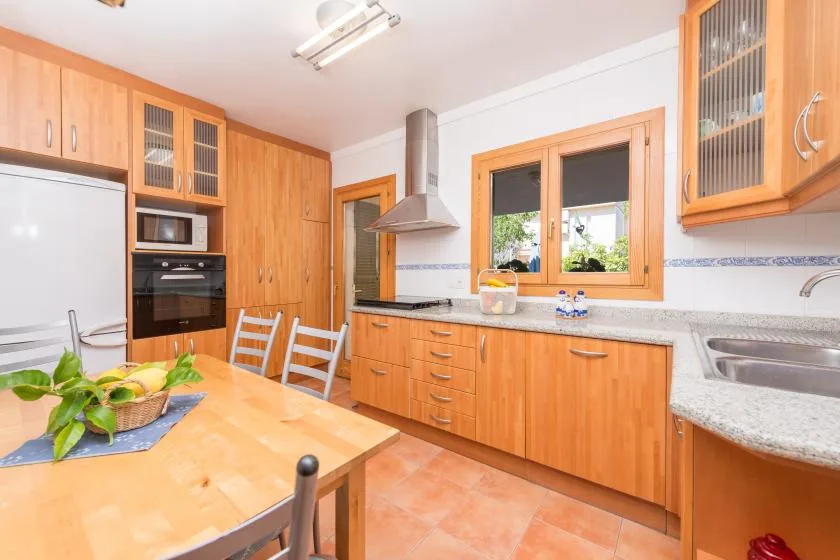 Una cocina luminosa con armarios de madera, una mesa de comedor y una ventana sobre la encimera.