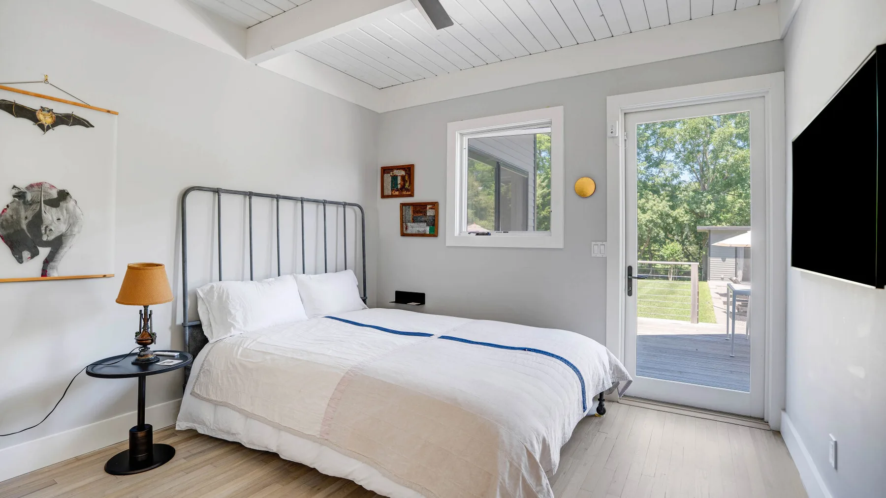 Un dormitorio con una cama bien tendida junto a una puerta de vidrio que da a una terraza.