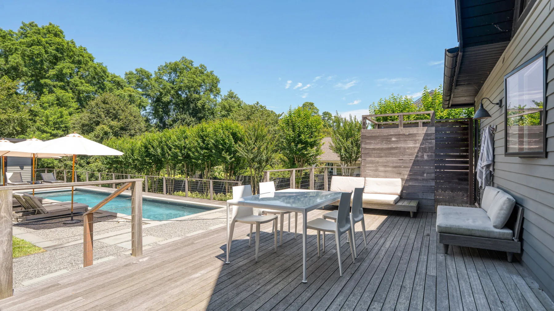 Una terraza soleada junto a la piscina, con mesa y asientos.