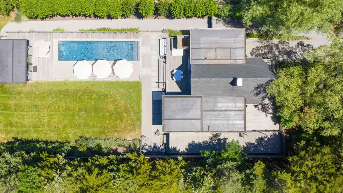 Una vista aérea muestra una piscina junto a una casa y un césped verde.