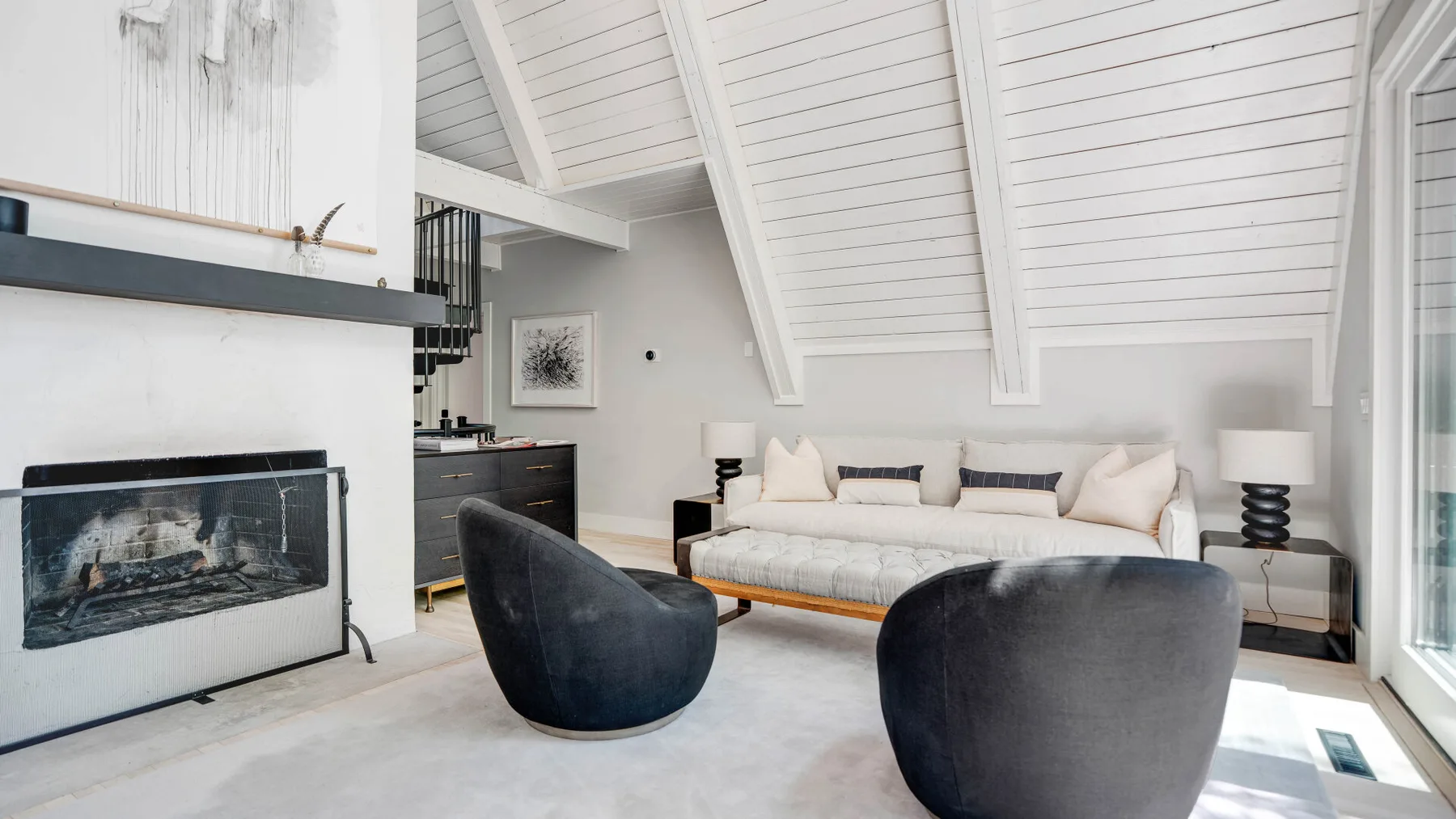Una sala luminosa con chimenea y sofá bajo un techo abovedado.