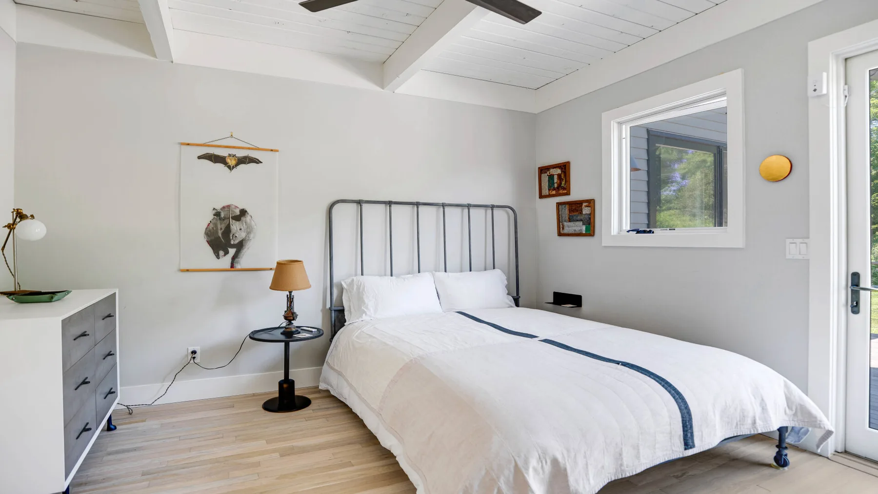 Un dormitorio con una cama, una mesa auxiliar y ventanas.