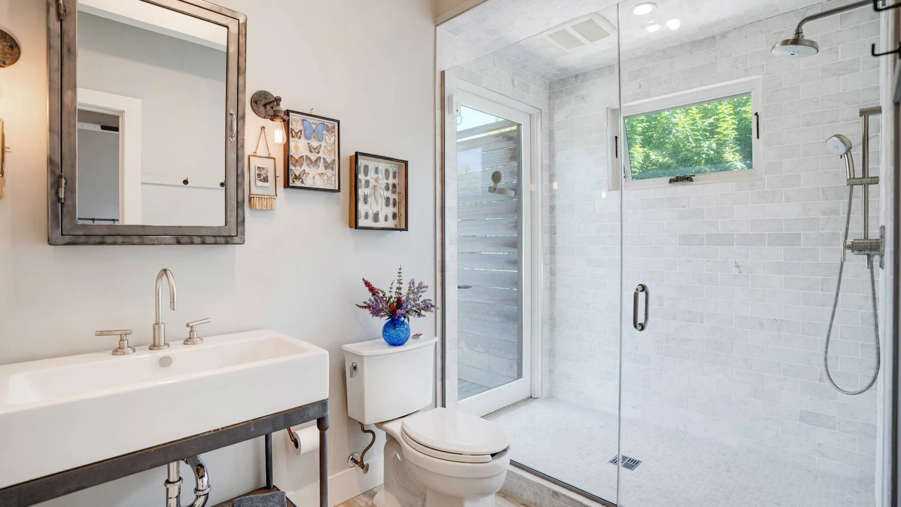 Un baño luminoso con lavabo, inodoro y ducha de vidrio.