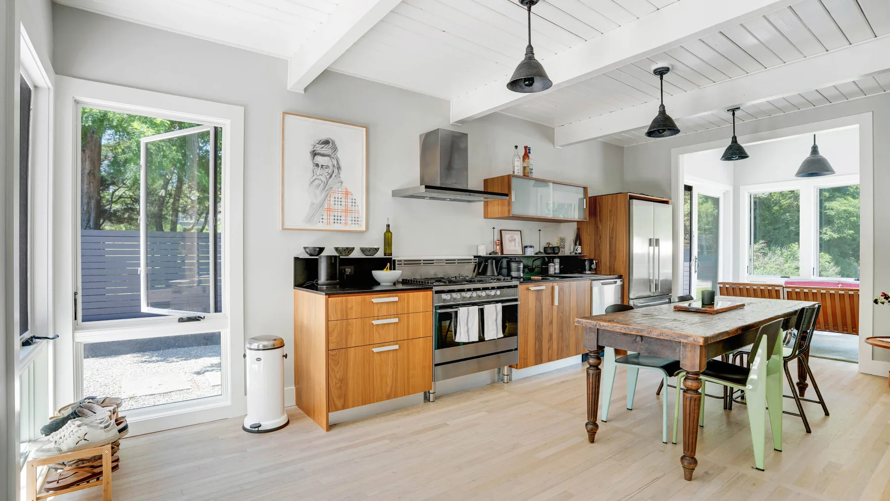 Una cocina y comedor luminosos con gabinetes de madera y una mesa.