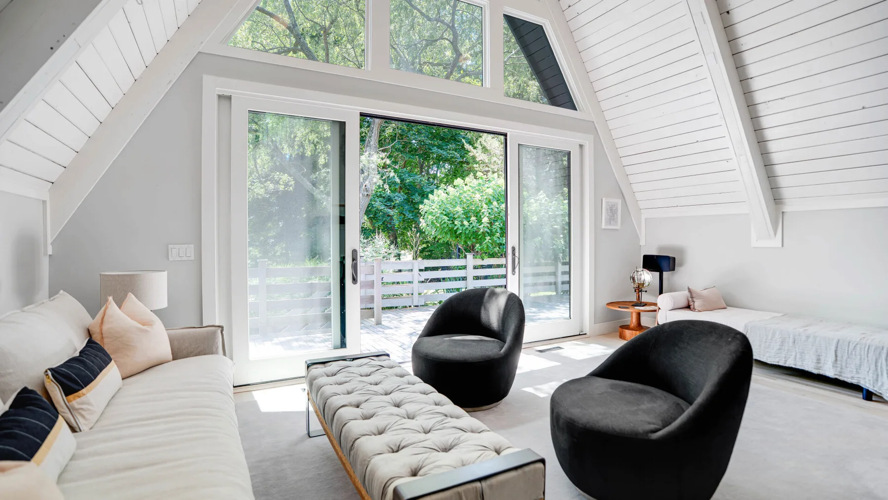 Una luminosa sala de estar abuhardillada con grandes ventanas, un sofá y asientos.