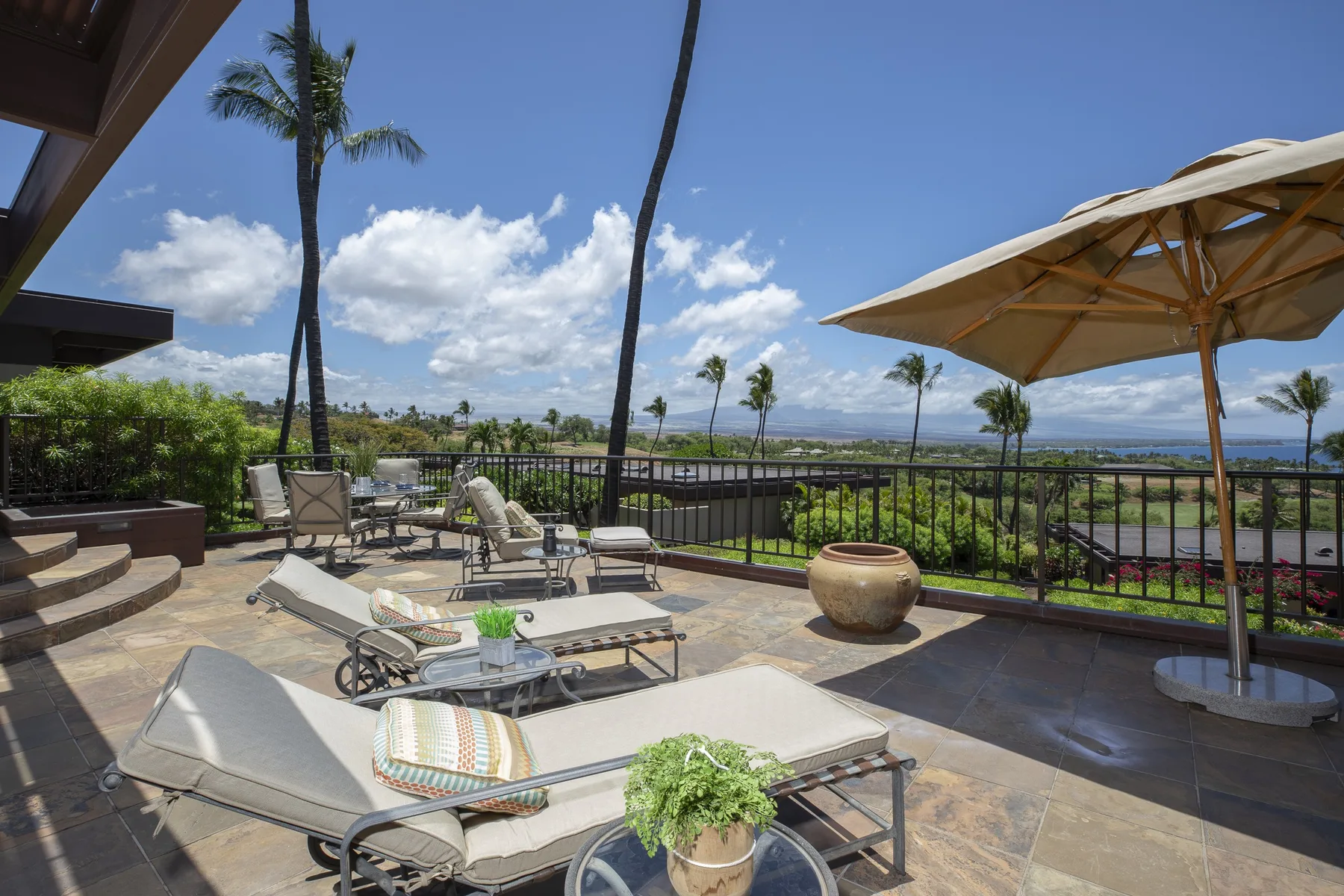 A sunny outdoor terrace with lounge seating and a large patio umbrella.