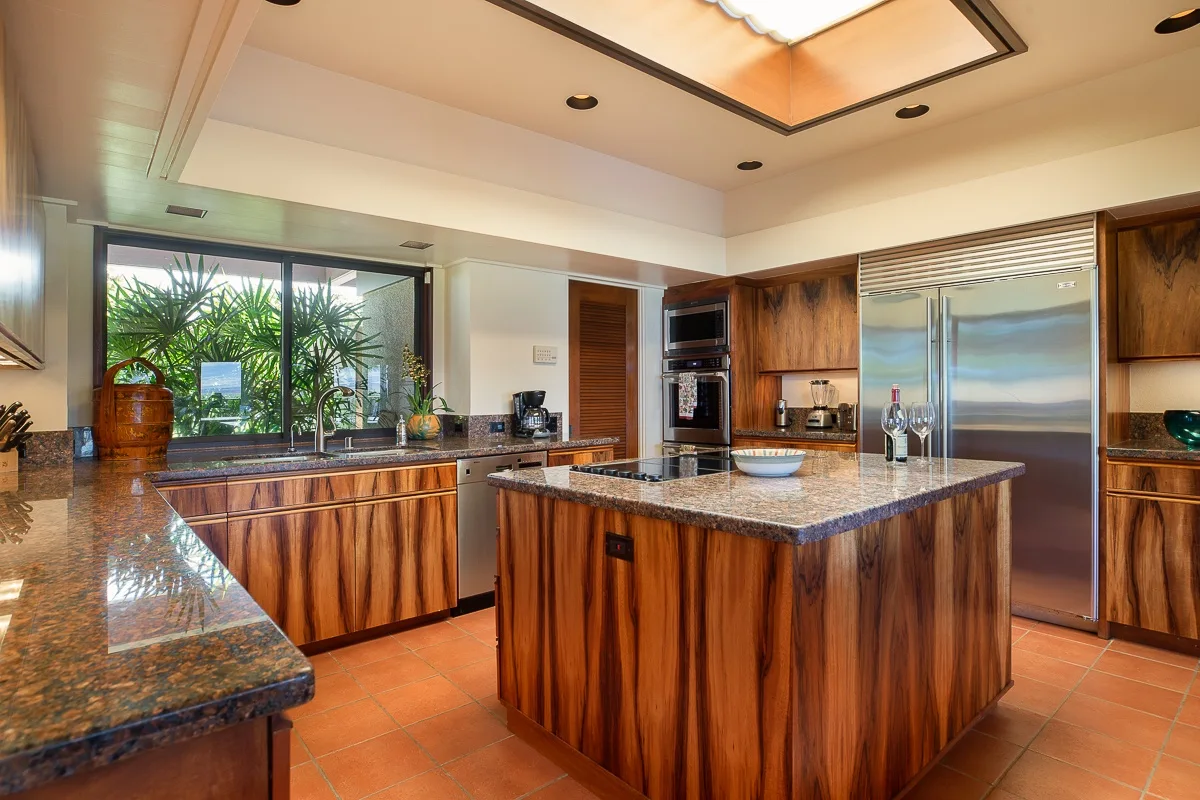 A spacious kitchen with wood cabinetry, stone counters, and a central island.