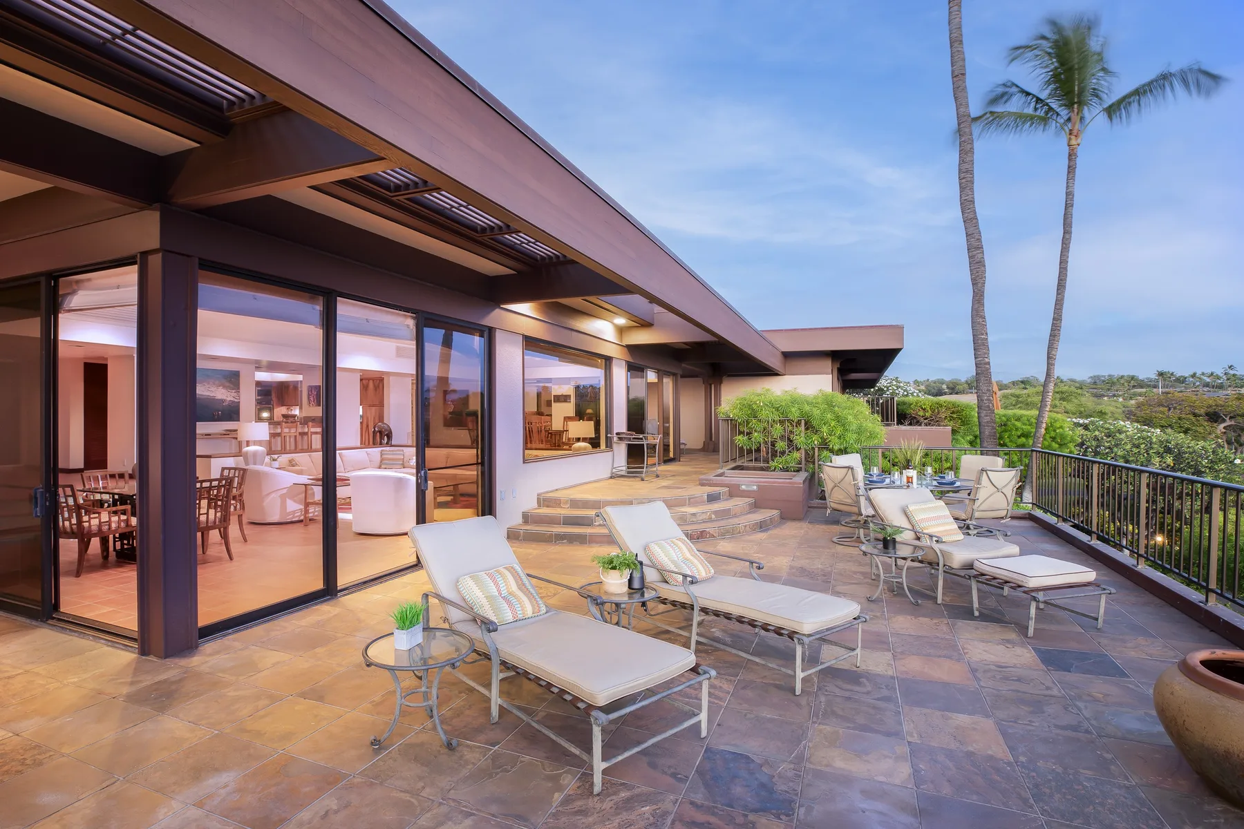 A stone patio with outdoor seating beside a glass-walled room.