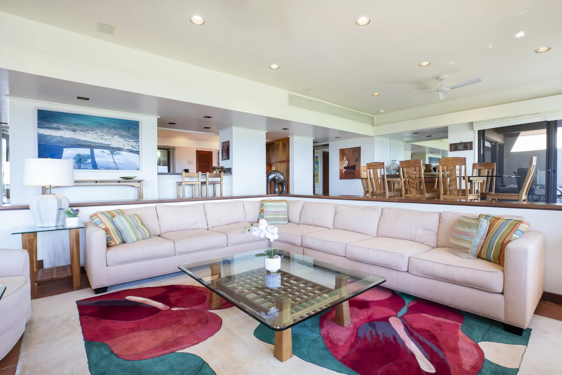 A spacious living room with an L-shaped seating area and a glass coffee table.