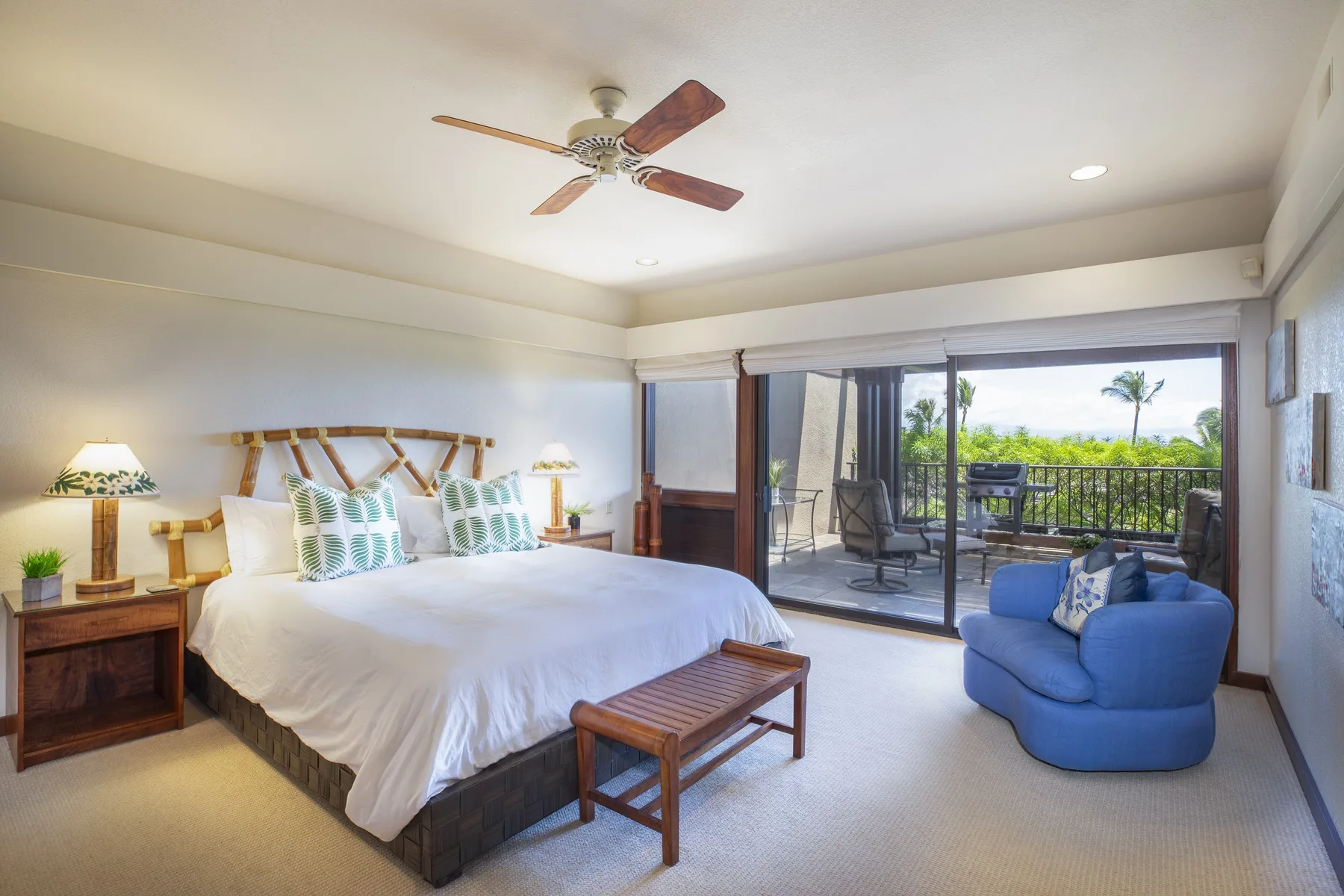 A bright bedroom with a large bed and sliding glass doors opening onto a balcony.
