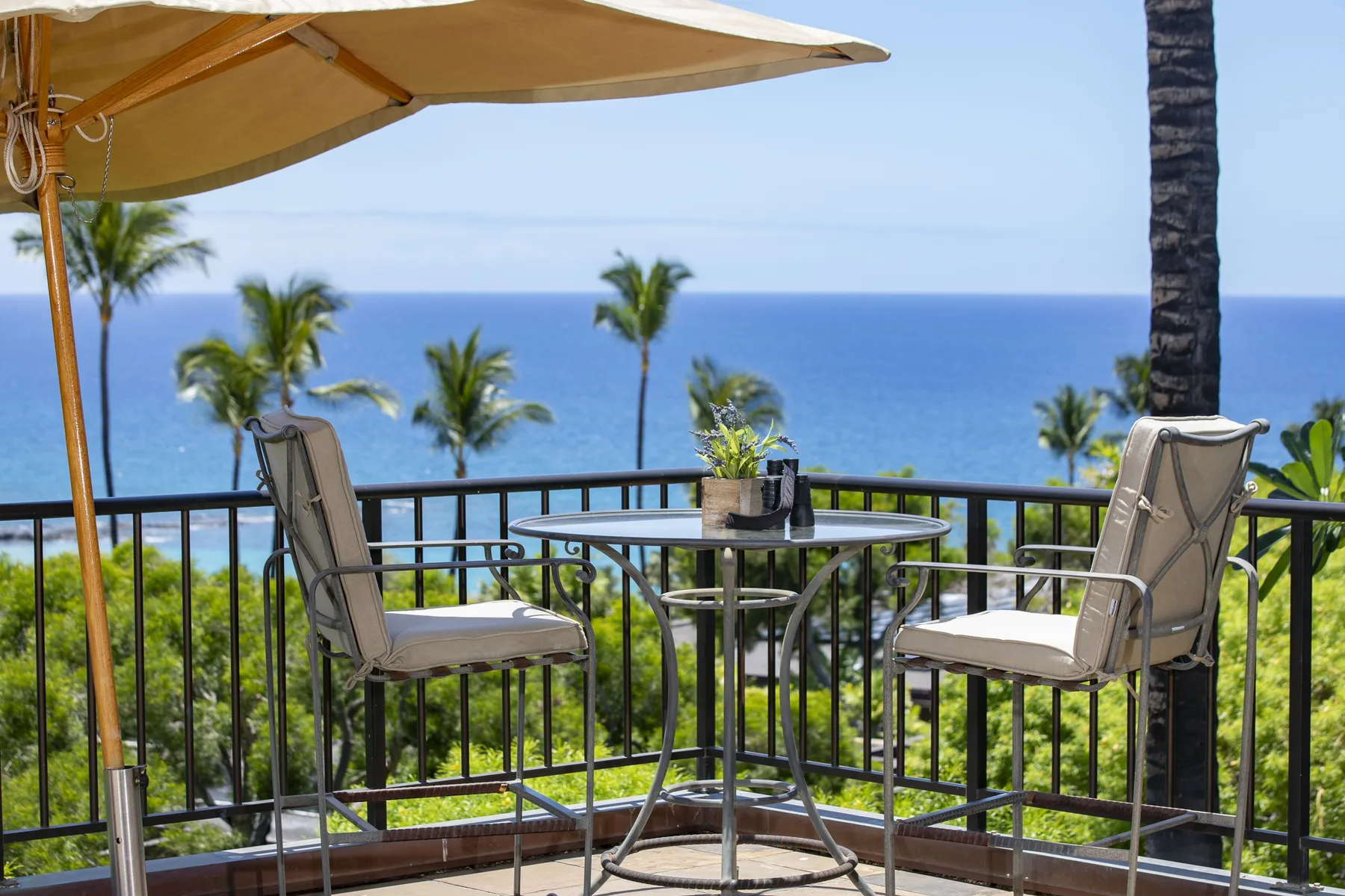 A balcony seating area with a small table overlooks the ocean.