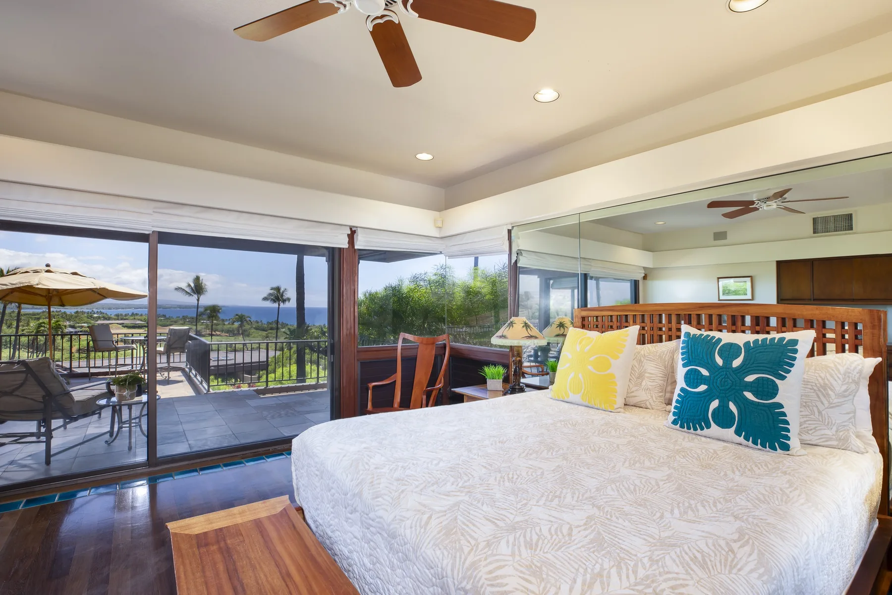 A bright bedroom with a large bed beside sliding glass doors opening onto a balcony.