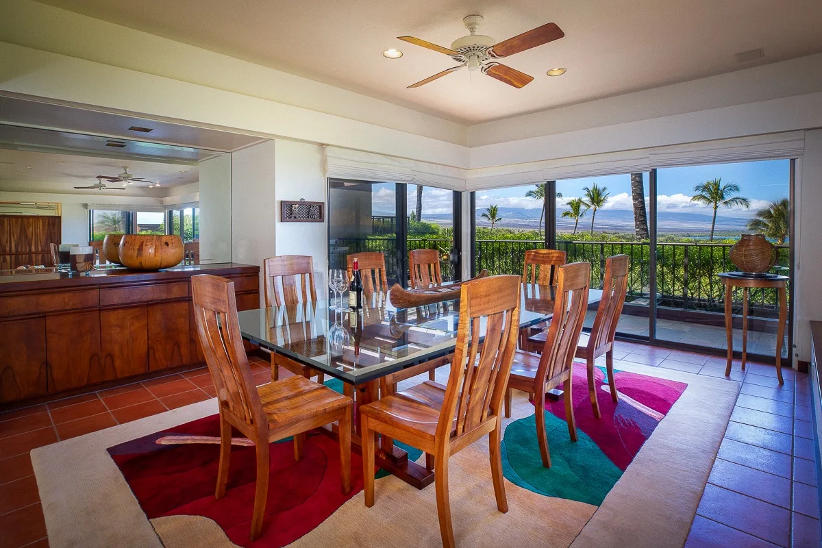 A dining area with wooden seating and large windows overlooking a balcony.