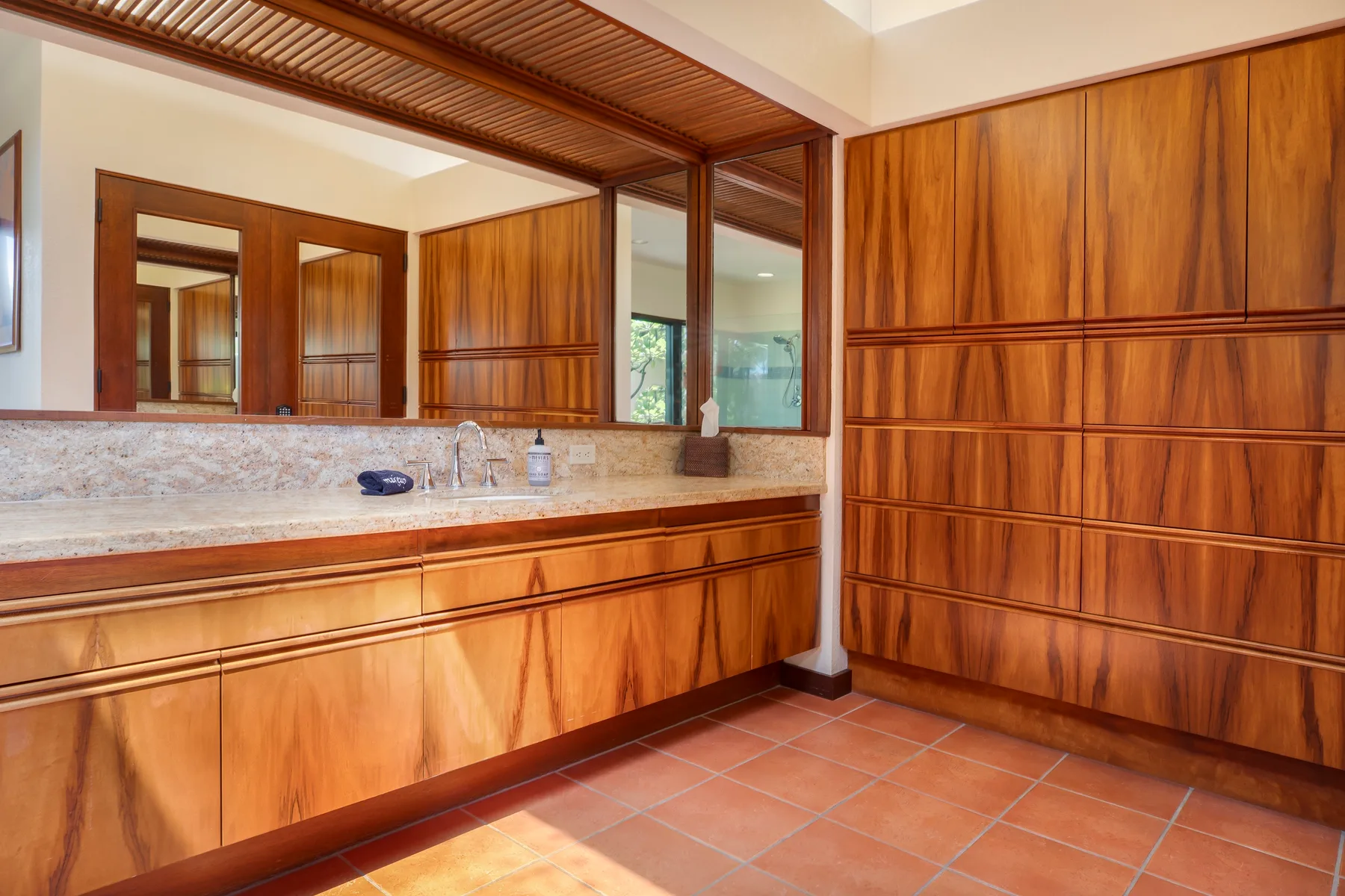 A wood-paneled bathroom vanity with a long countertop and mirror.