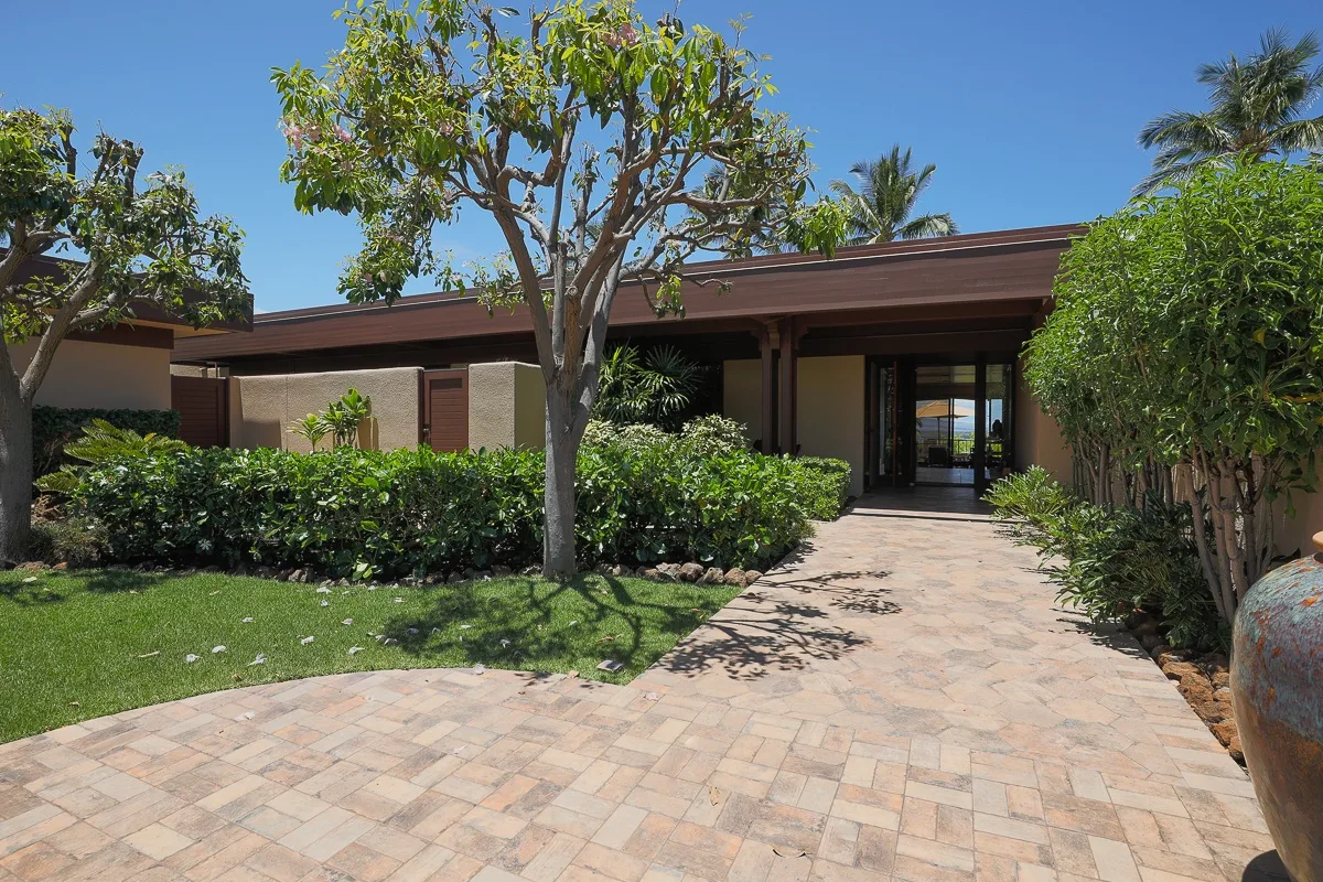 A paved walkway leads through landscaped greenery to a modern single-story building.
